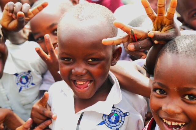 Pupils smiling and waving outside their classroom